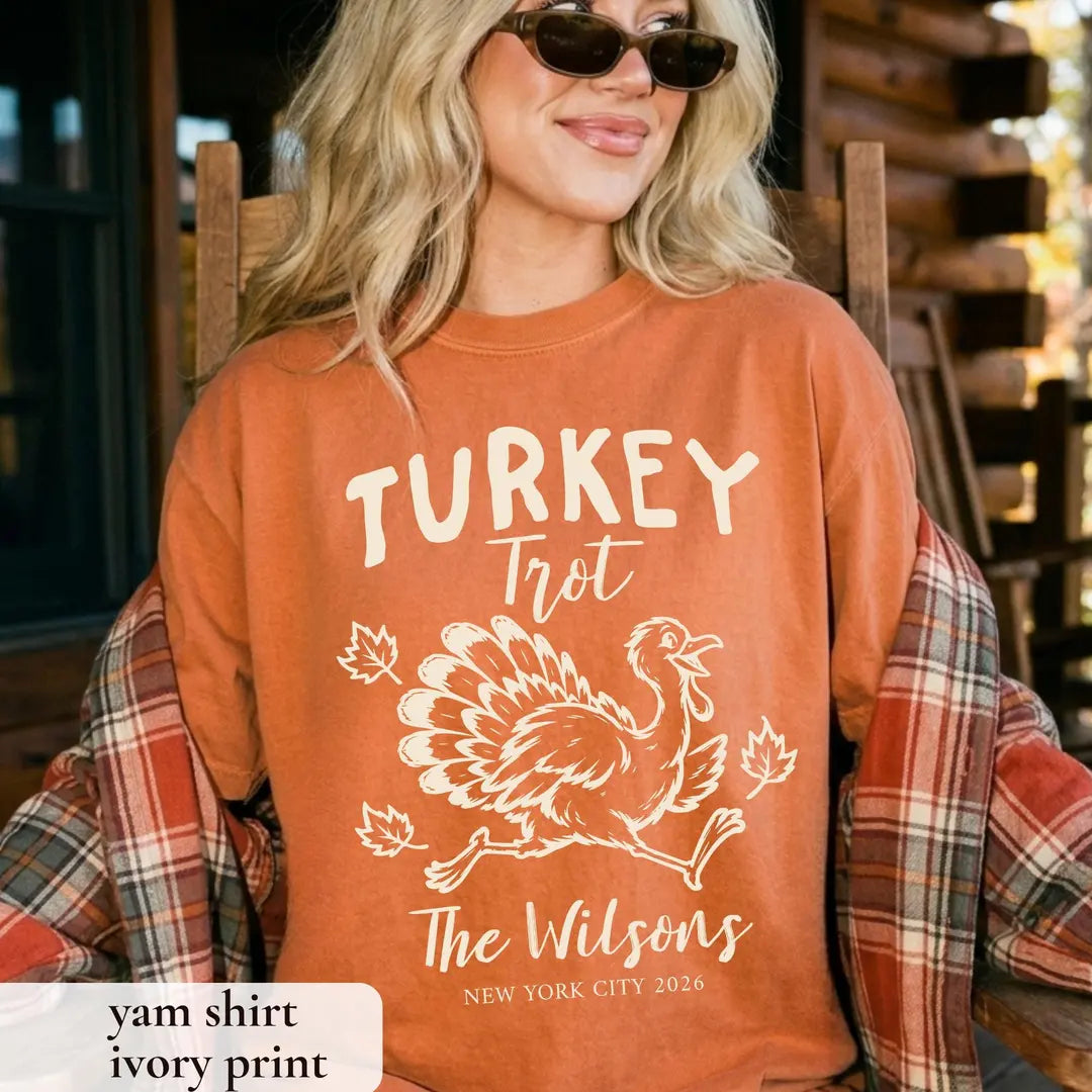 Woman in sunglasses and a Yam orange Comfort Colors tee with a plaid flannel, ivory Turkey Trot and a running turkey