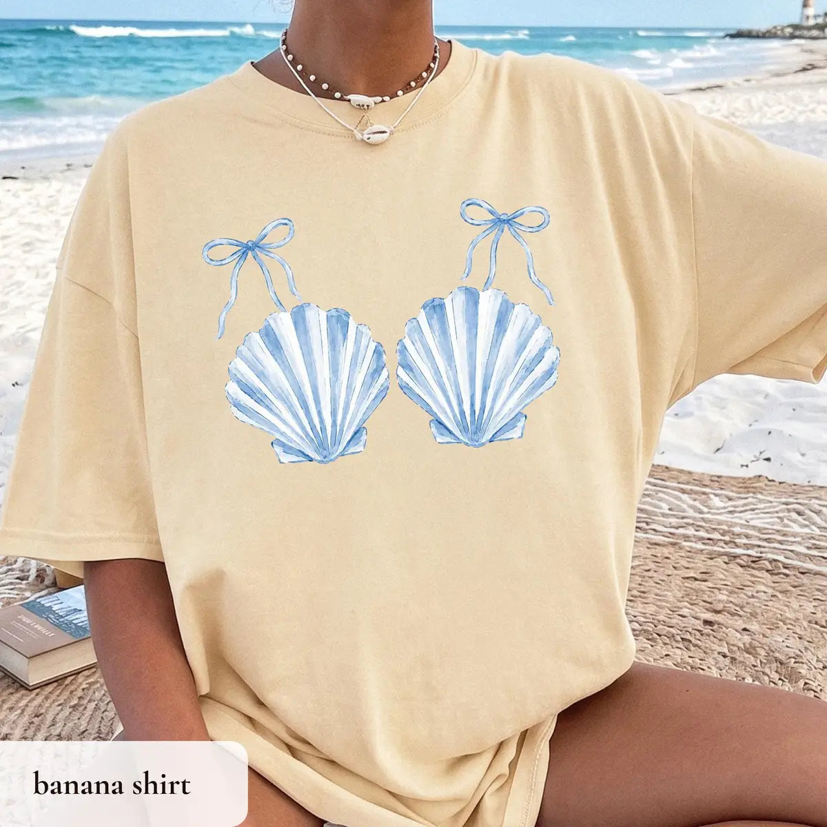 Woman in a Banana yellow Comfort Colors tee on a beach blanket, blue striped scallop shells with tiny bows