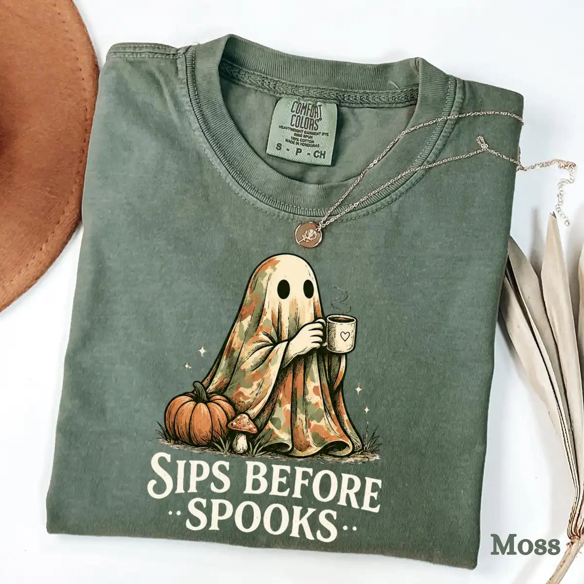 Comfort Colors T-shirt flatlay in Moss color featuring Sips Before Spooks camo ghost graphic