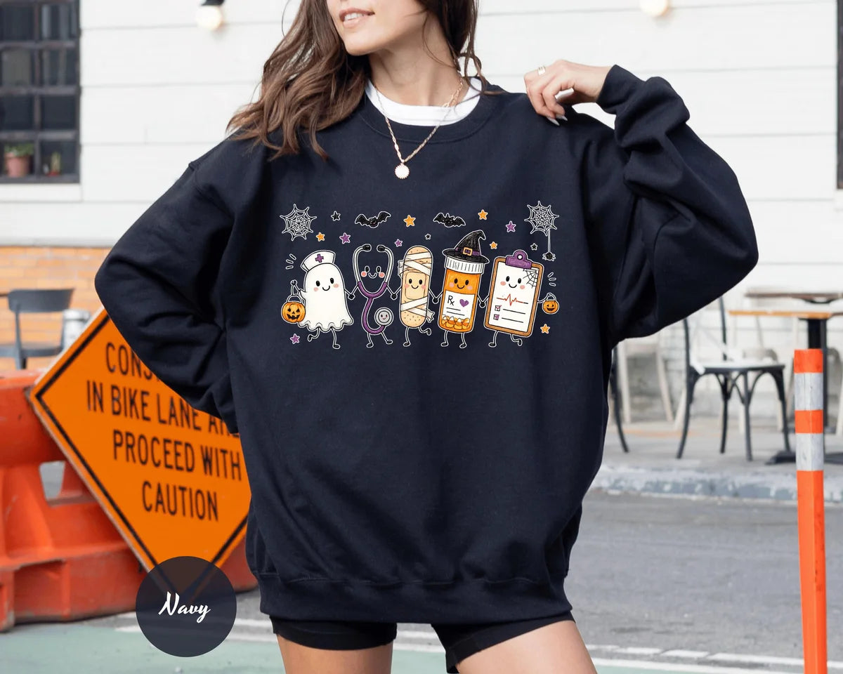 Navy crewneck sweatshirt with a ghost, stethoscope, bandage and medical chart characters with Halloween details, worn by a model.