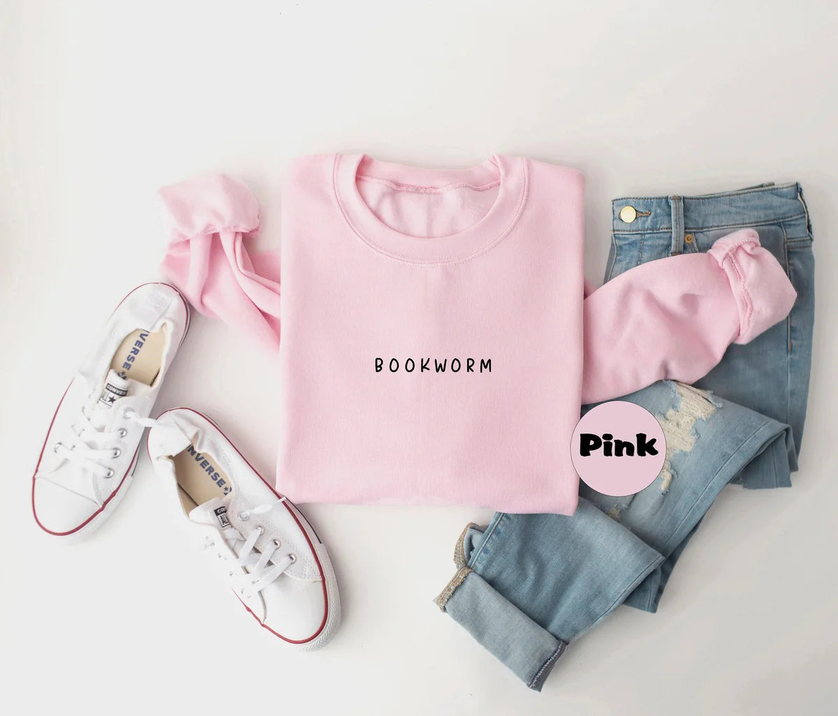 Light Pink crewneck sweatshirt with small minimal lettering that reads bookworm on the chest, flat lay view.