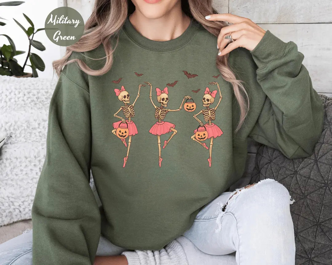 Military Green crewneck sweatshirt with printed three ballerina skeletons in pink tutus with pumpkins and bats, worn by a model.
