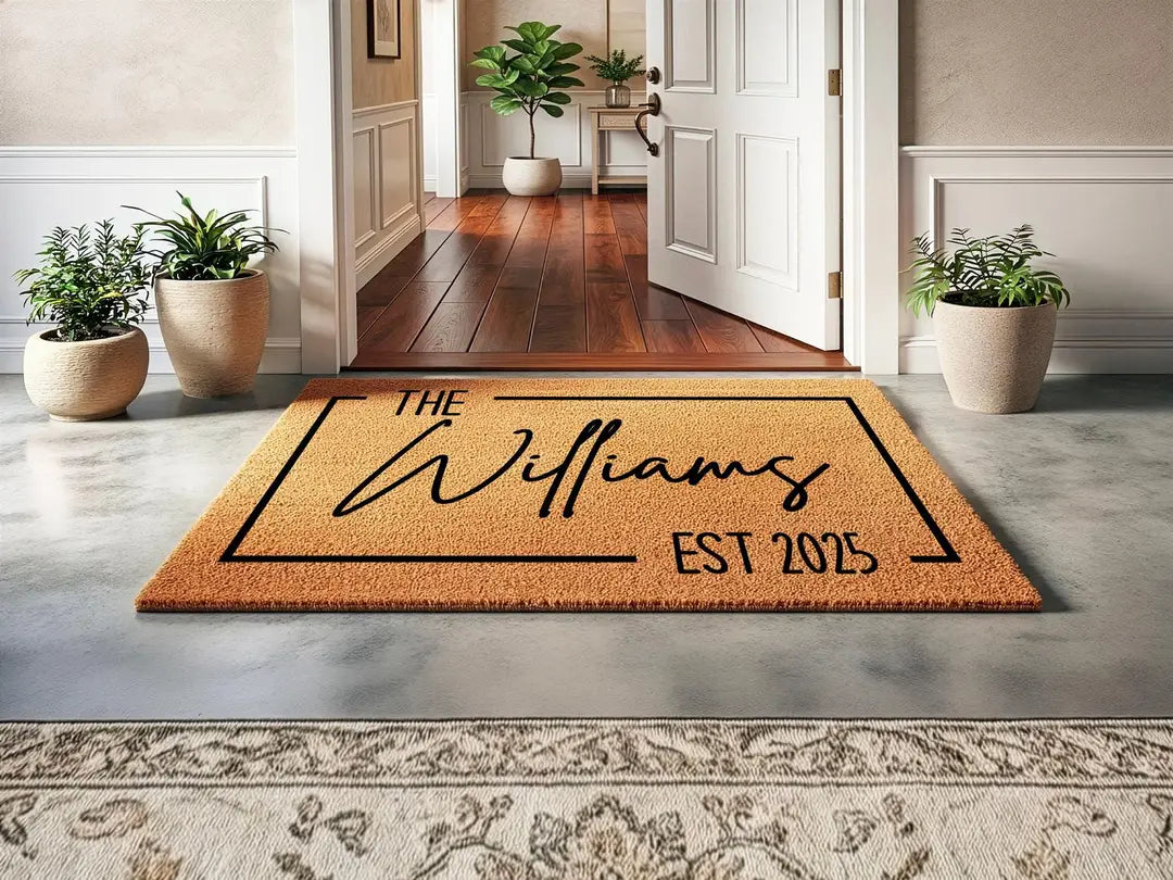 Coir doormat with a framed family name and established year inside an entry hall with potted plants and an open door