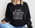 Black Crewneck sweatshirt with I'm Not Retired I'm A Professional Grandma design, alternate product view.