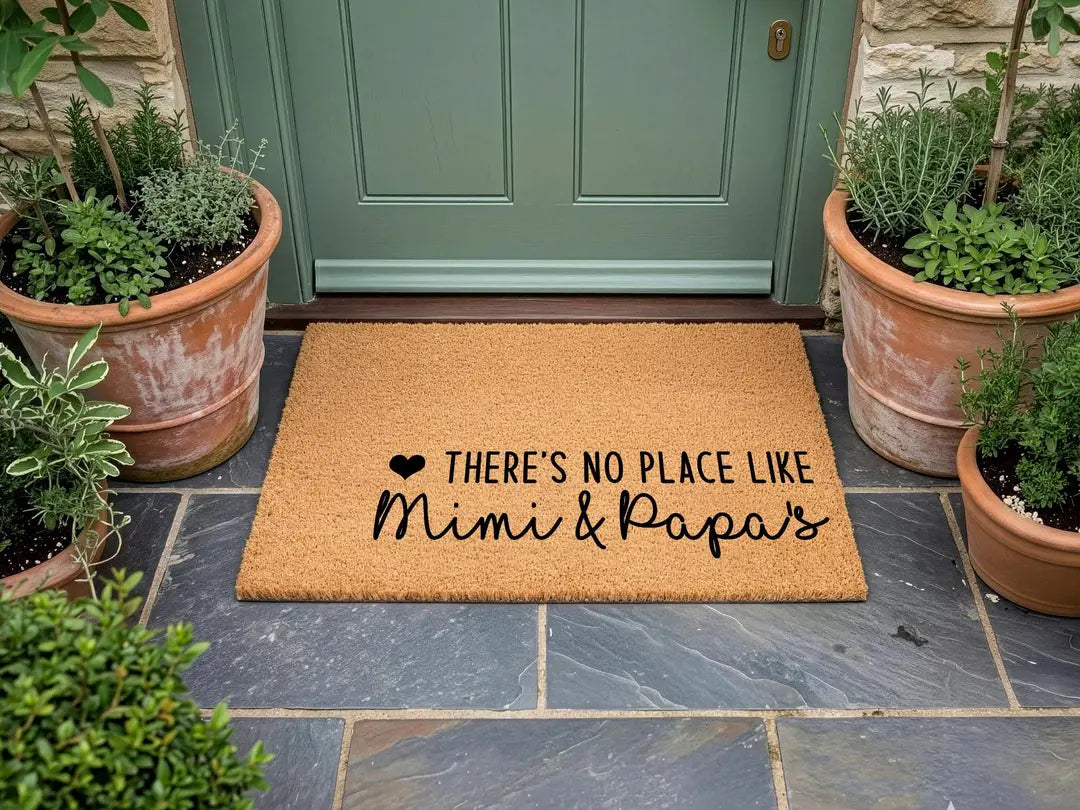 Coir doormat with a There's No Place Like Mimi and Papa's message at a sage green door with terracotta herb pots