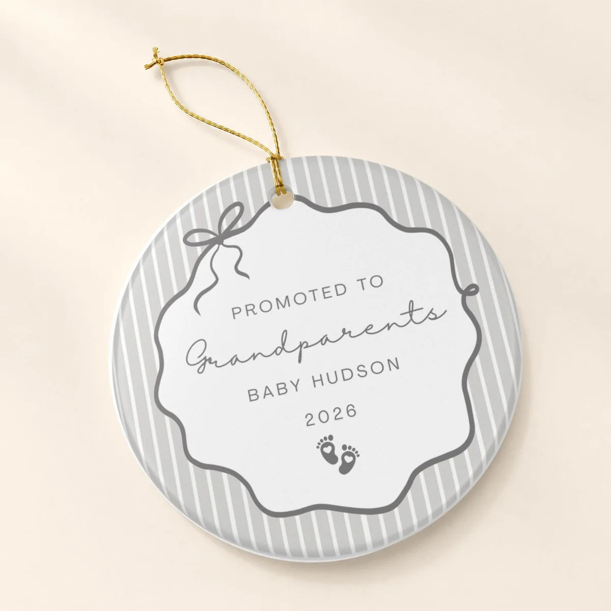 Gray pinstripe round ceramic Promoted to Grandparents ornament with a bow frame, baby footprints, and a personalized name and year on a cream background