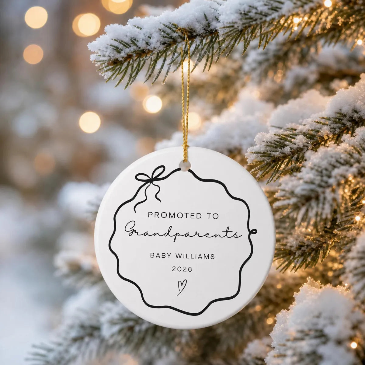 Black wavy bow frame round ceramic Promoted to Grandparents ornament hanging from a snow-covered evergreen branch