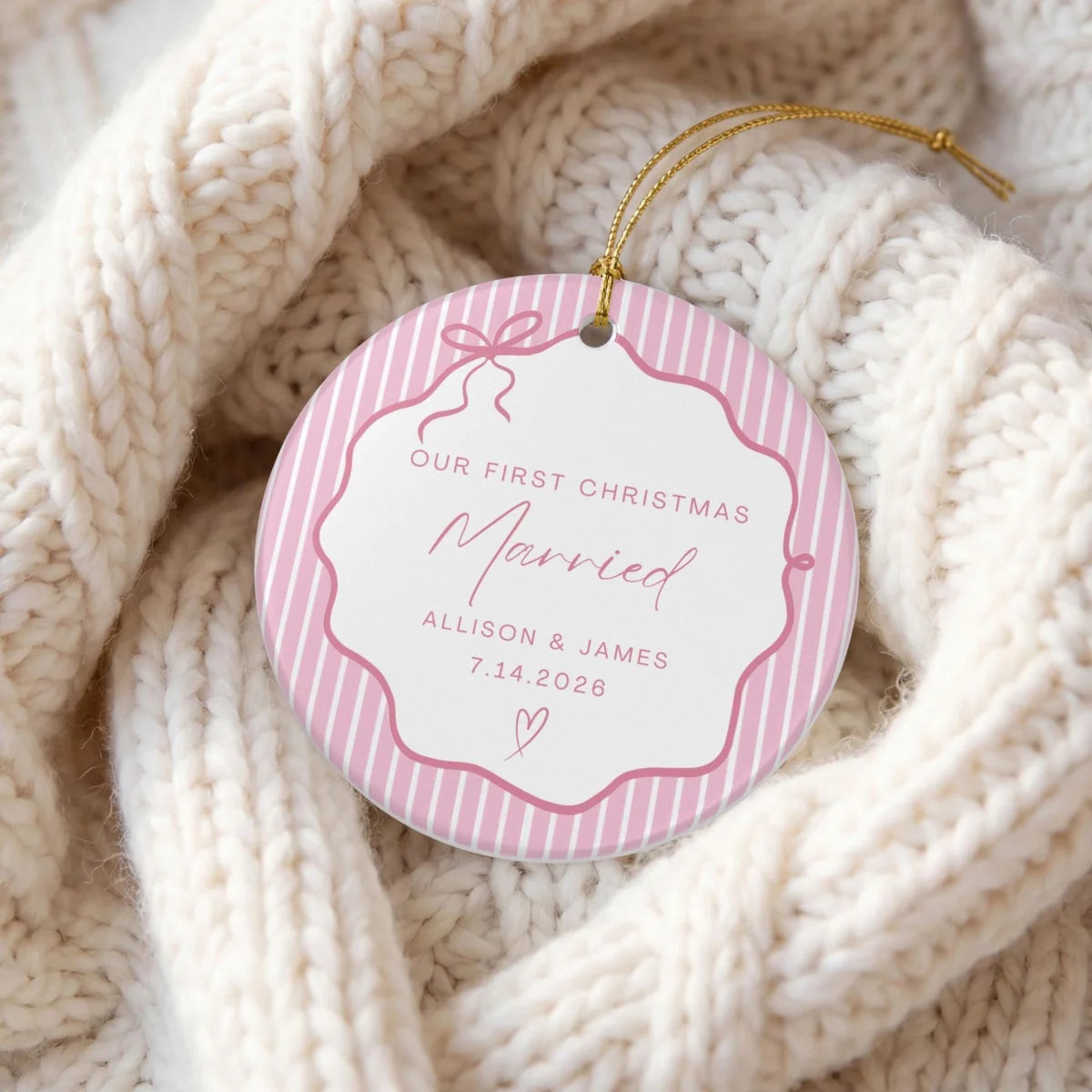 Pink pinstripe round ceramic First Christmas Married ornament with personalized names and date on a cream knit blanket