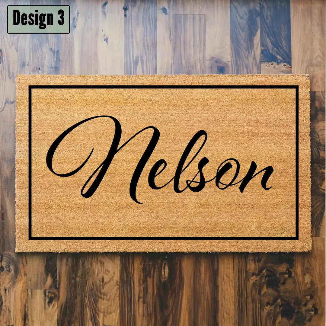 Coir doormat with a framed script family name on a dark wood plank floor