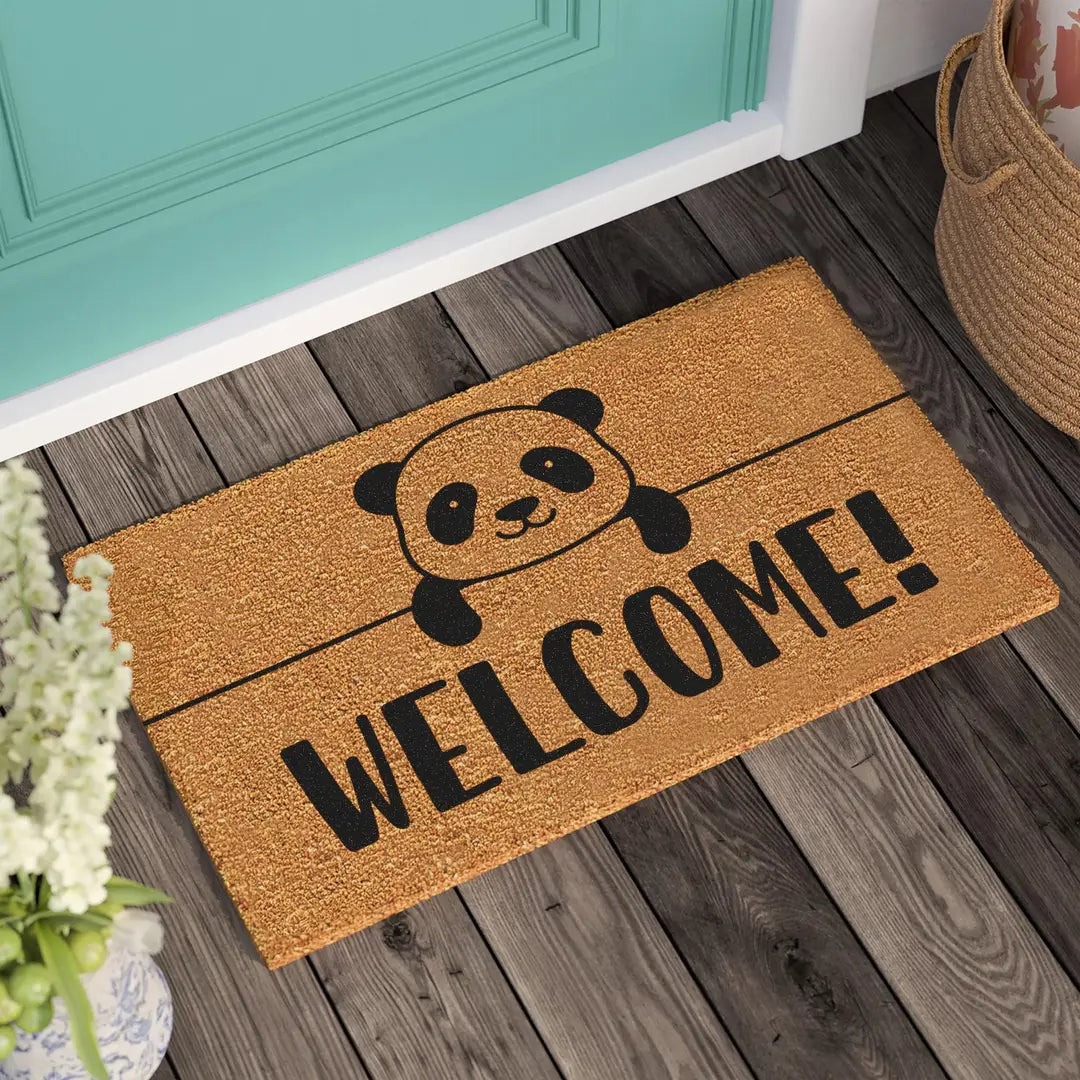 Rectangular coir doormat with a peekaboo panda and bold WELCOME lettering in front of a teal door