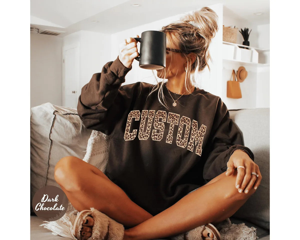 Dark Chocolate crewneck sweatshirt with bold leopard print varsity lettering with your own custom name or text, worn by a model.