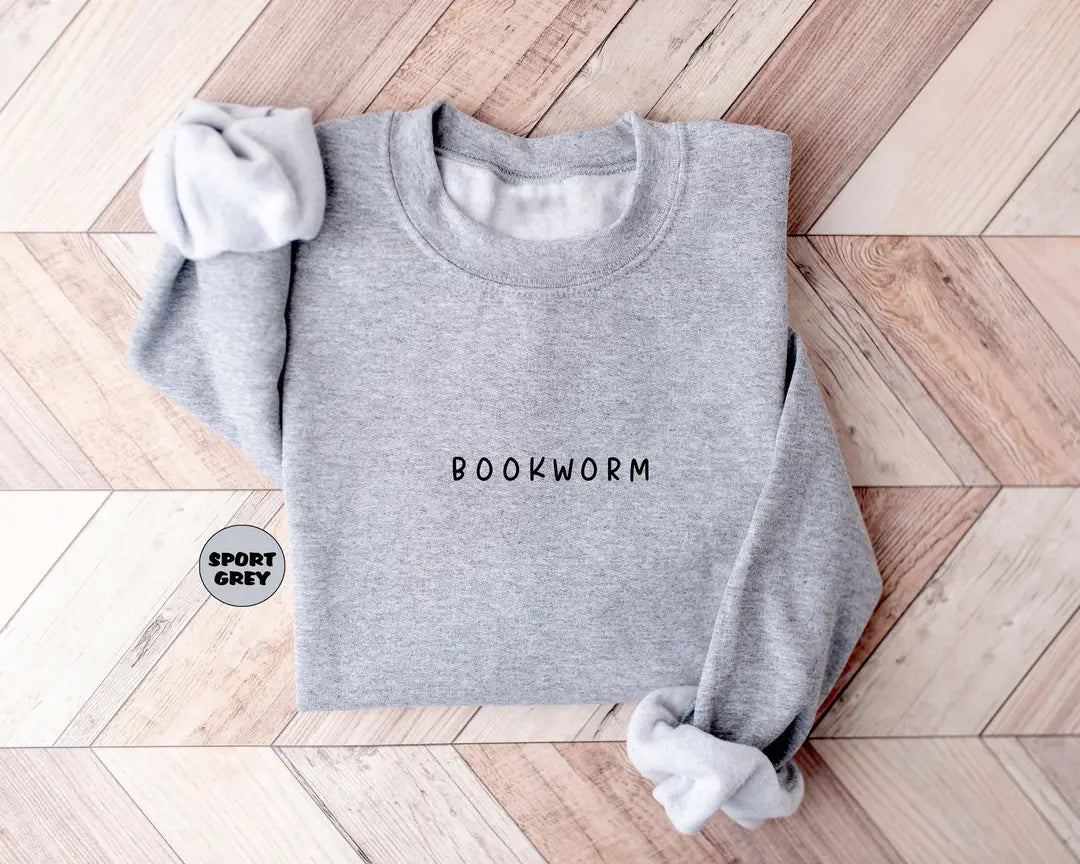 Sport Grey crewneck sweatshirt with small minimal lettering that reads bookworm on the chest, flat lay view.