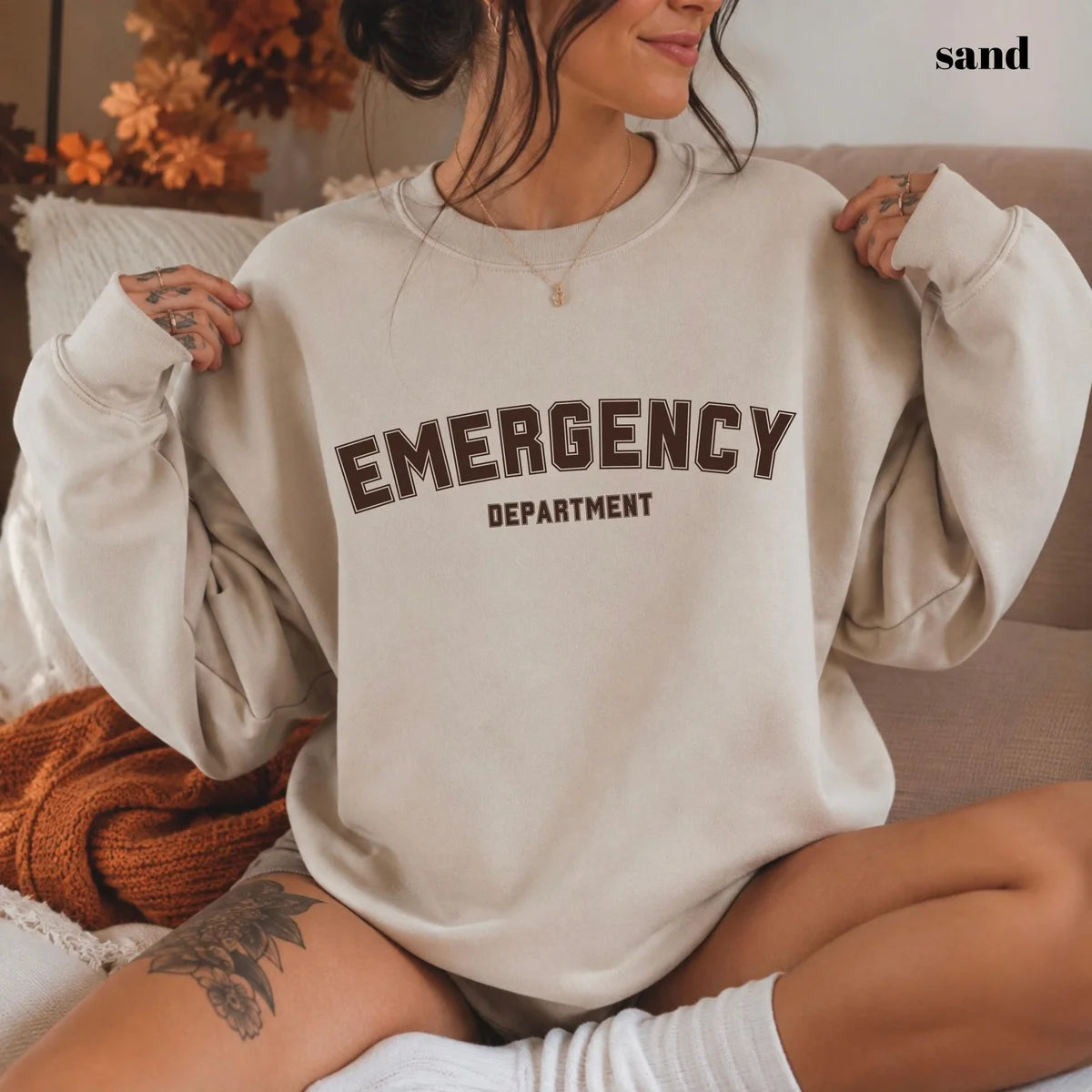 Sand crewneck sweatshirt with printed varsity style emergency department lettering, worn by a model.