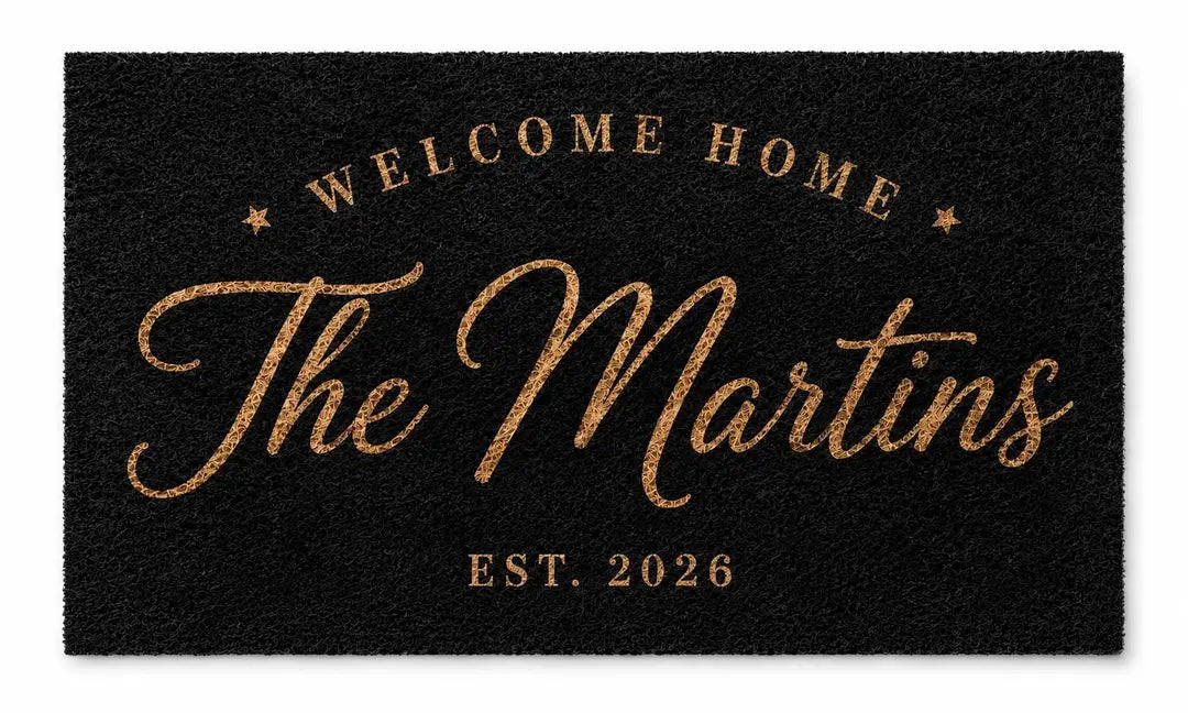Flat view of a black faux coir doormat with an arched Welcome Home line, script family name, and established year