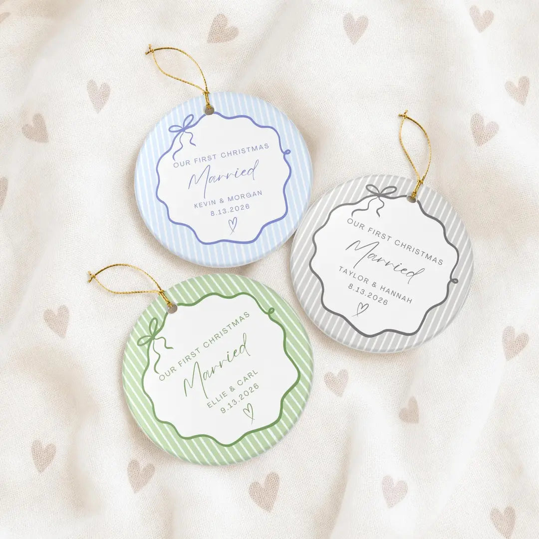 Blue, gray, and green pinstripe round ceramic First Christmas Married ornaments on a cream heart-print fabric