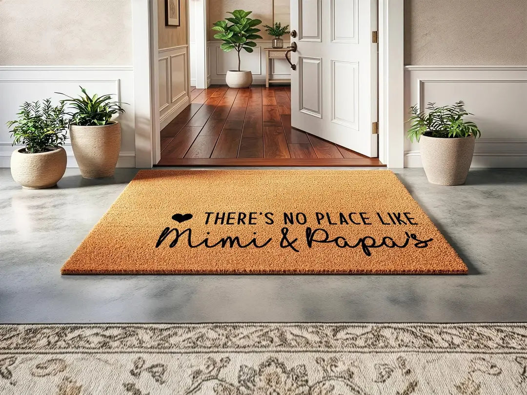 Coir doormat with a There's No Place Like Mimi and Papa's message inside an entry hall with potted plants and an open door