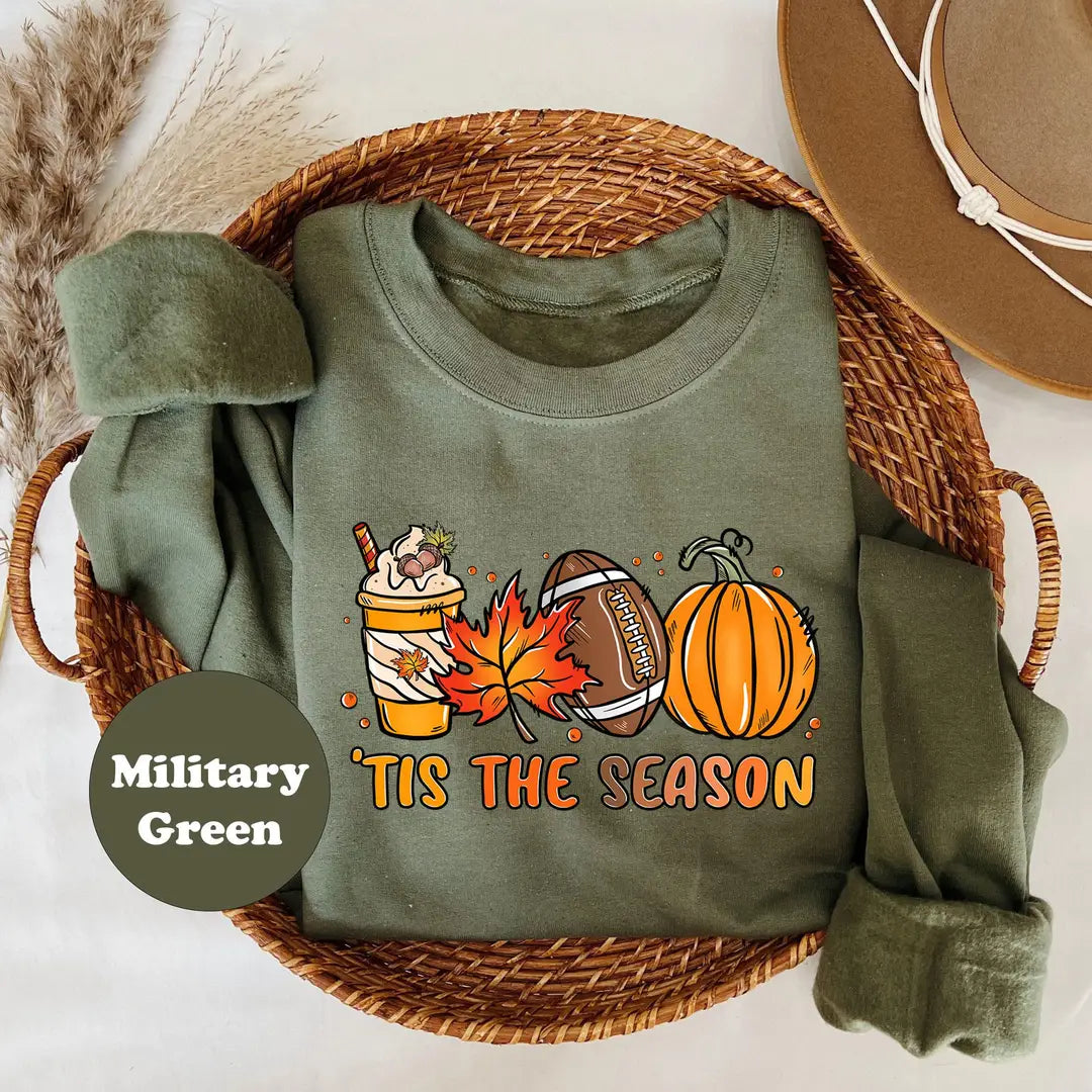 Military Green crewneck sweatshirt with a latte, autumn leaves, a football and a pumpkin above the words tis the season, flat lay view.