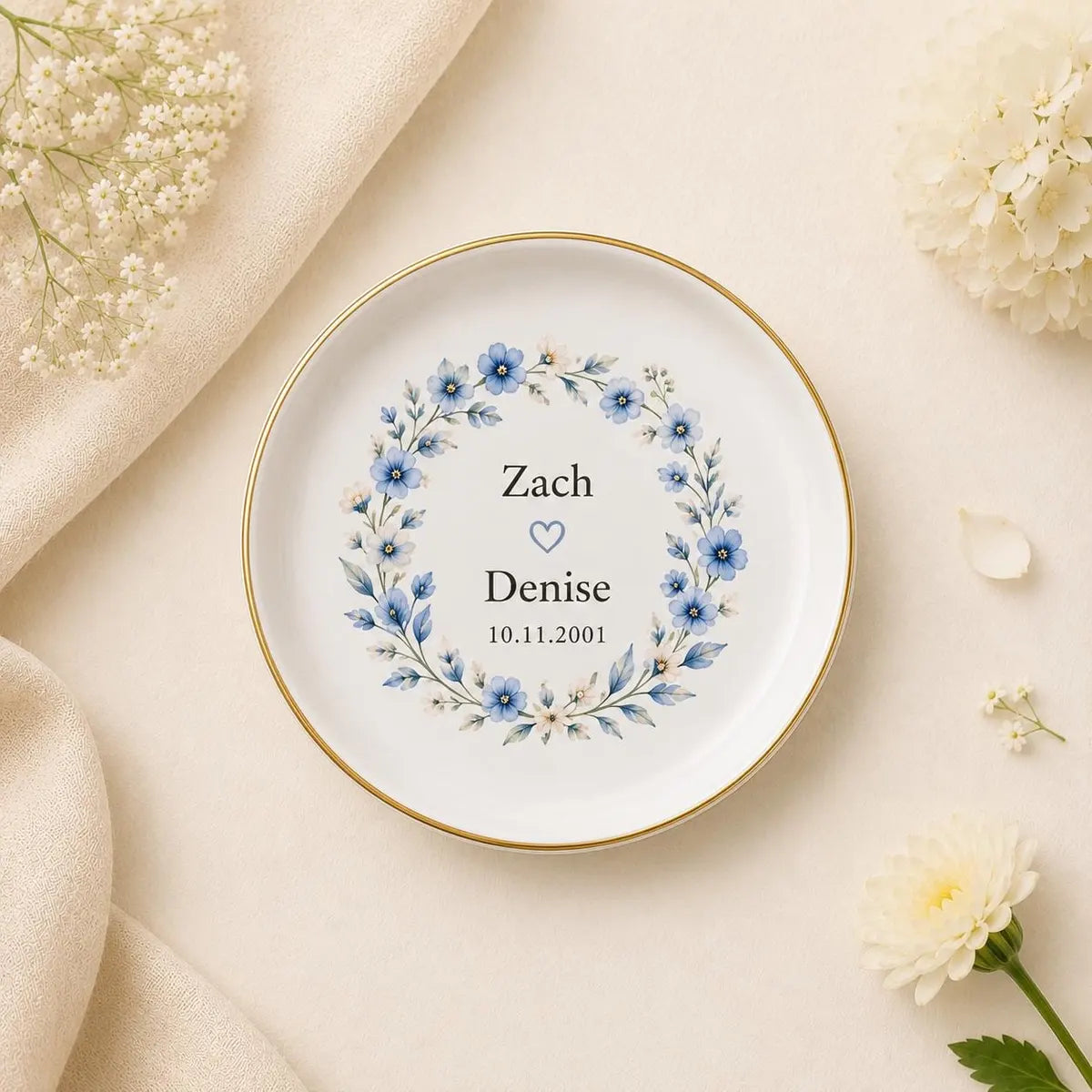 Round ceramic couples ring dish with a blue floral wreath, custom names, and date styled with cream flowers
