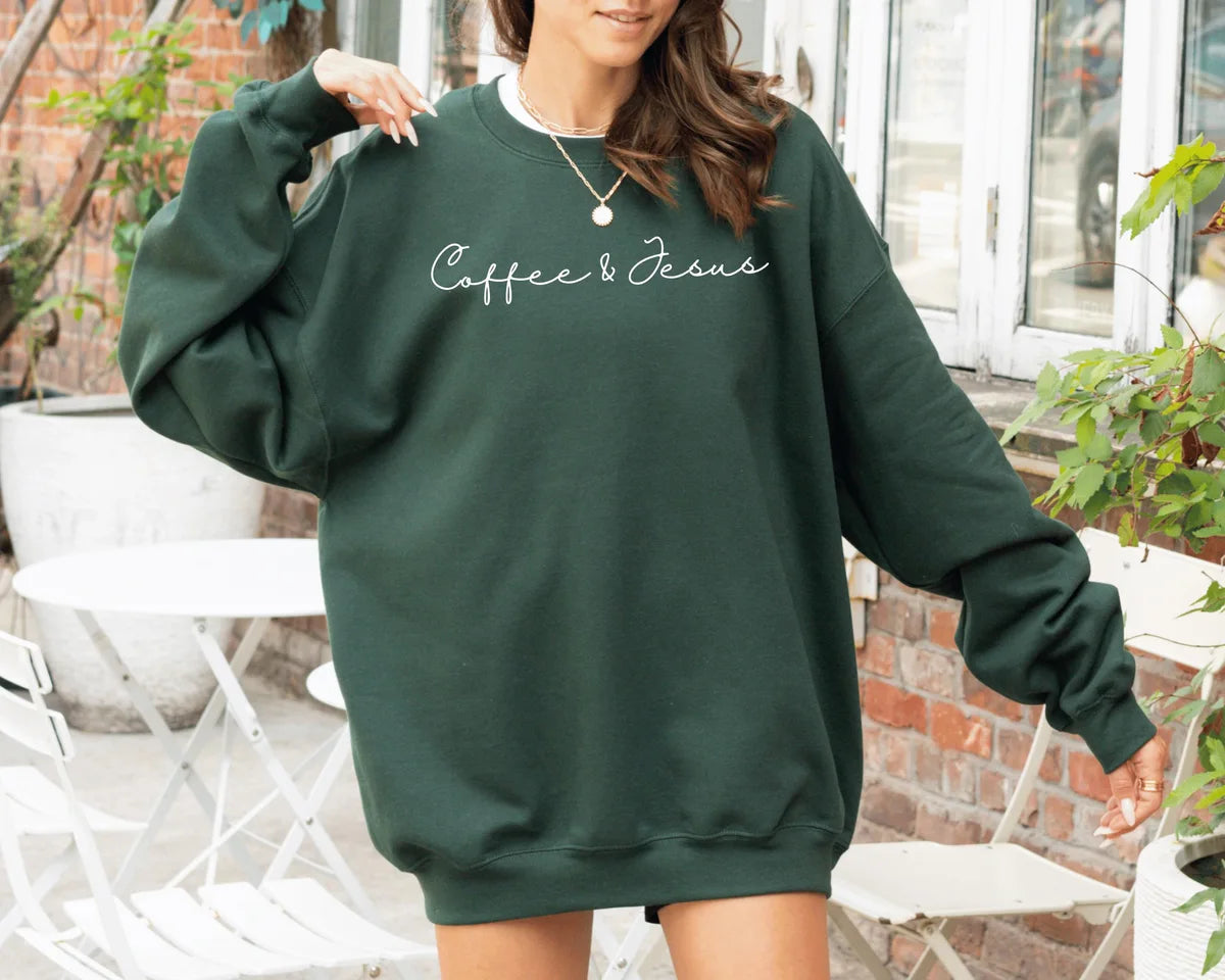 Forest Green crewneck sweatshirt with minimal script lettering that reads coffee & Jesus, worn by a model.
