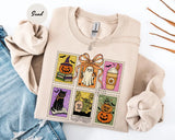 Sand crewneck sweatshirt with six vintage postage-style stamps with a ghost, black cat, pumpkins and a coffee cup, flat lay view.