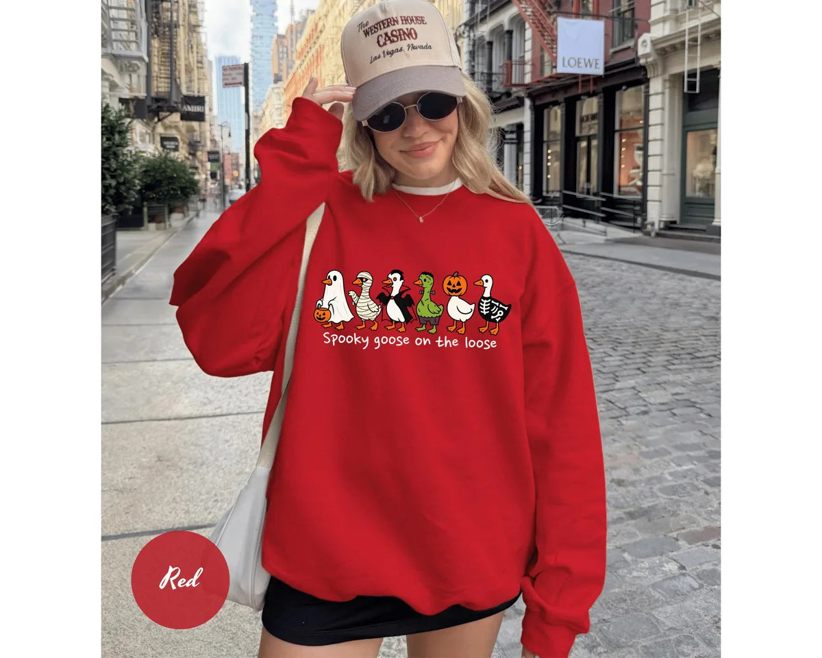 Red GD crewneck sweatshirt with costumed geese dressed as a ghost, vampire, pumpkin and skeleton above the words spooky goose on the loose, worn by a model.