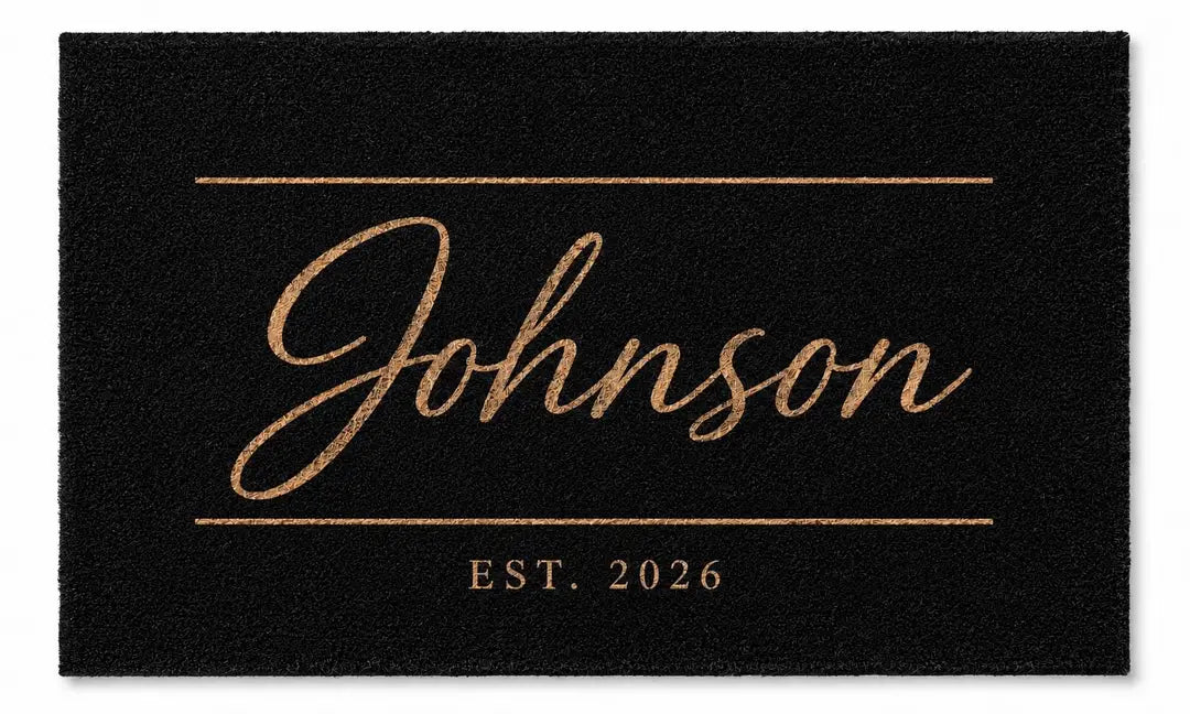 Flat view of a black faux coir doormat with a script surname between two thin gold-tone lines and an established year