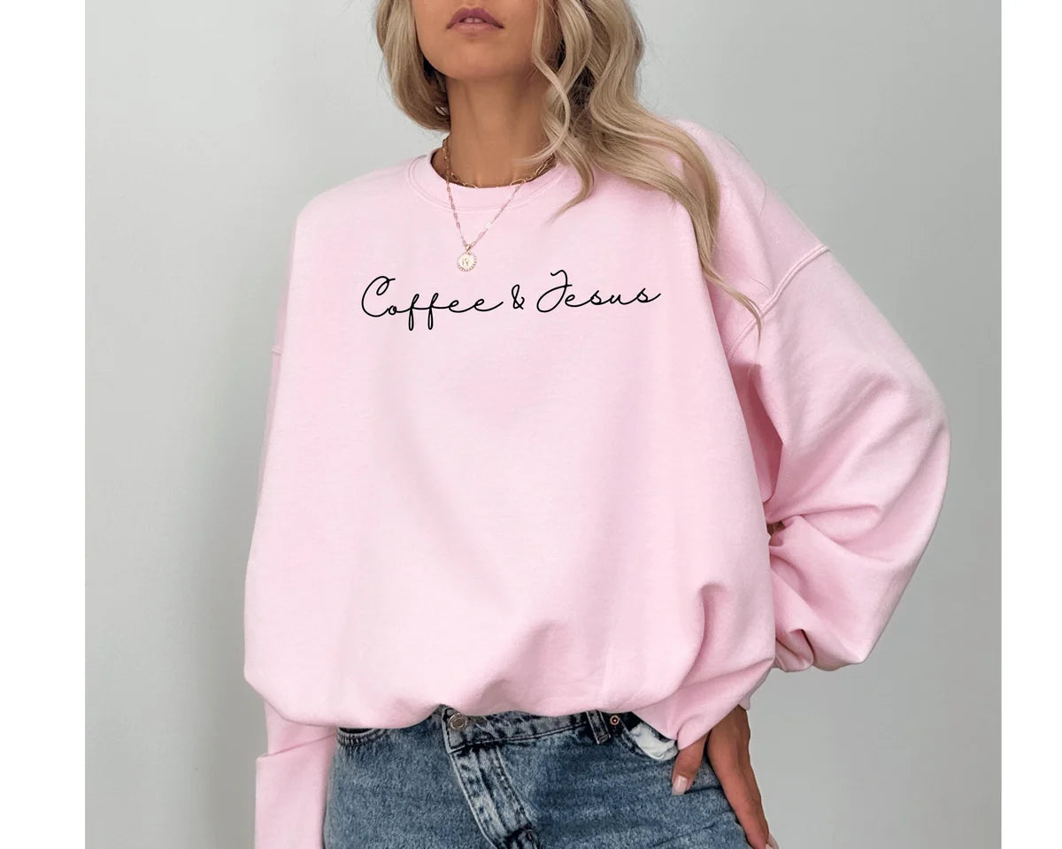 Light Pink crewneck sweatshirt with minimal script lettering that reads coffee & Jesus, worn by a model.