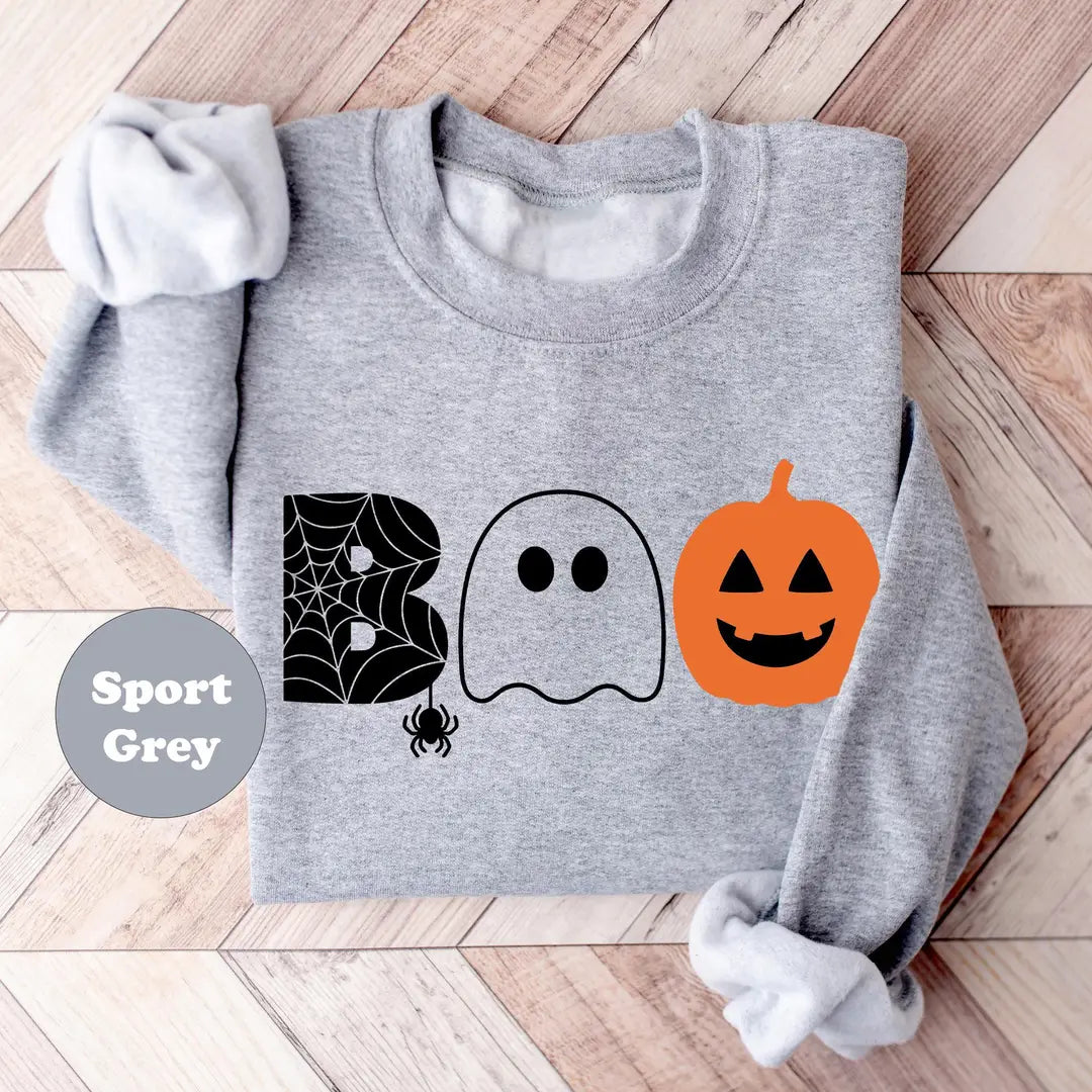 Sport Grey crewneck sweatshirt with the word boo spelled with a spider web letter, a ghost and a jack-o-lantern, flat lay view.