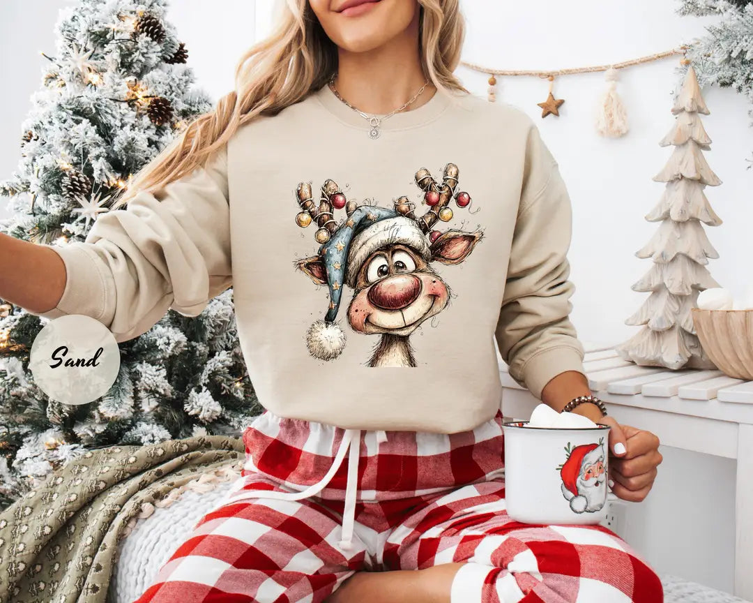 Sand crewneck sweatshirt with a retro reindeer wearing a knit hat with ornament antlers, worn by a model.