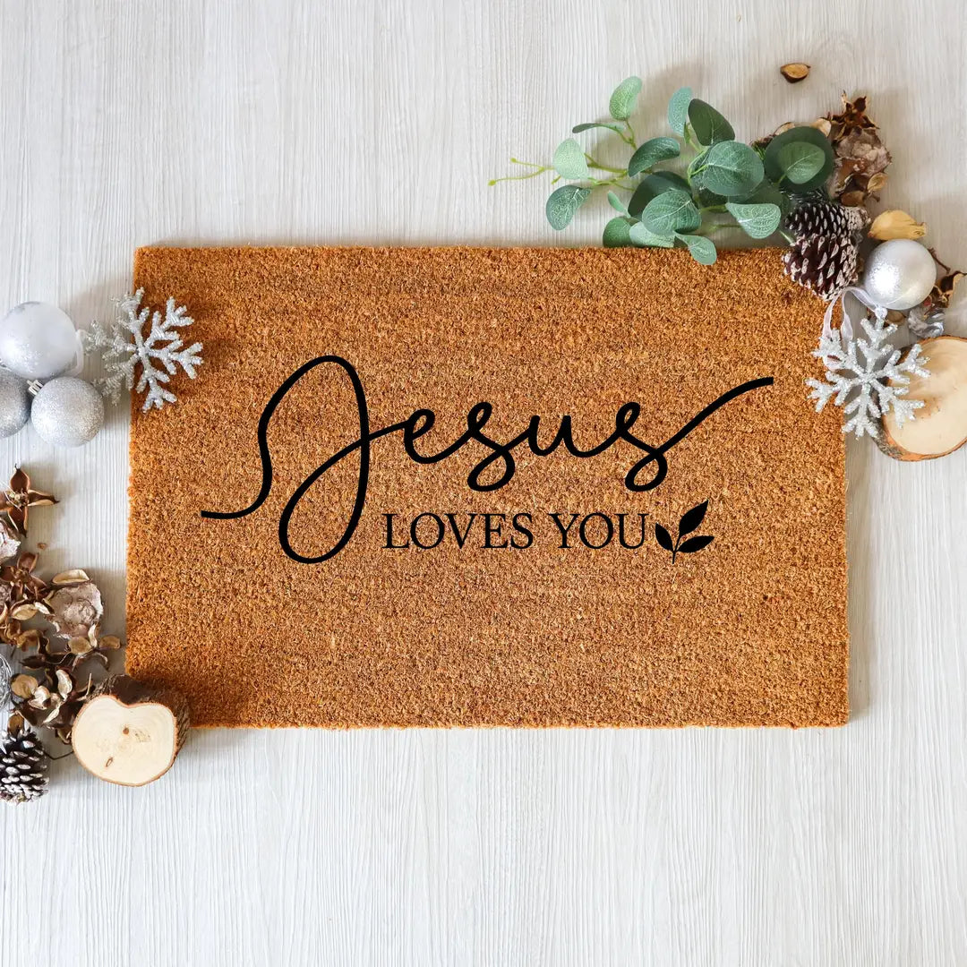 Coir doormat with Jesus Loves You script lettering styled with eucalyptus, pinecones, and silver ornaments