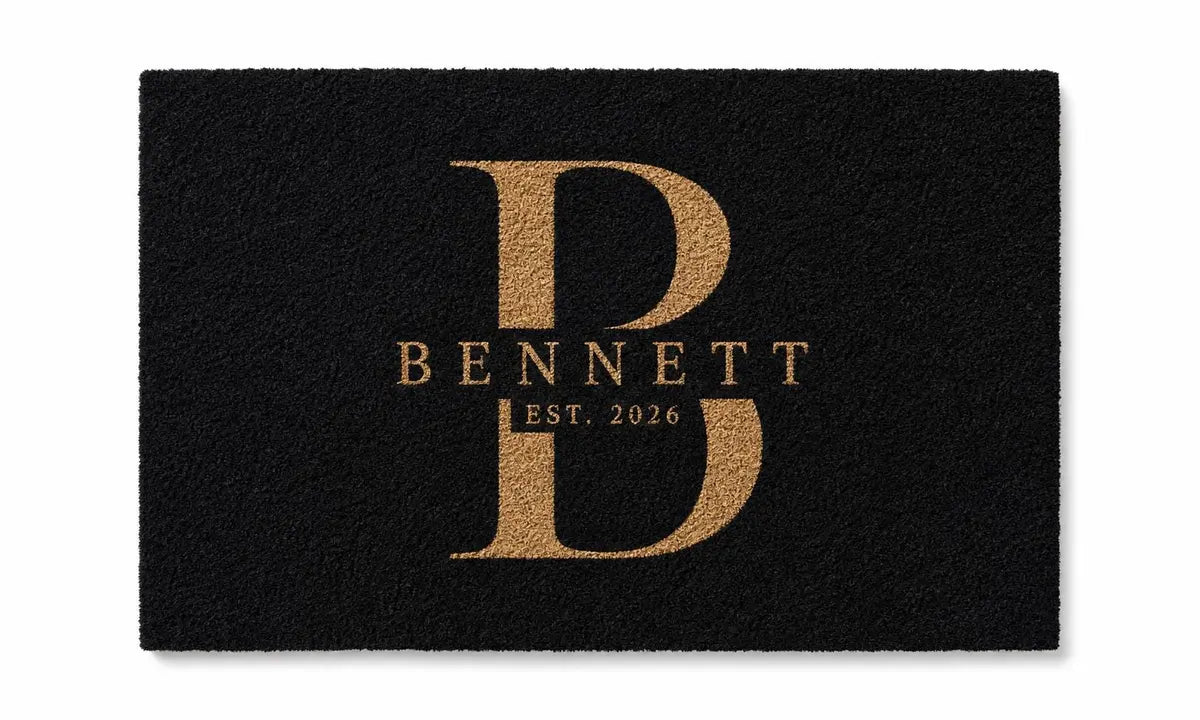 Flat view of a black doormat with a gold monogram B, Bennett name, and established year