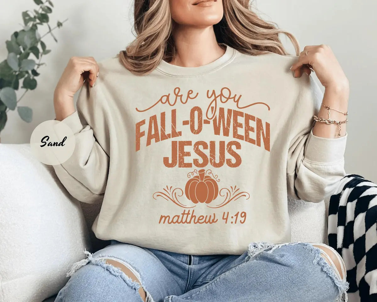 Sand crewneck sweatshirt with printed a pumpkin with the words are you fall-o-ween jesus and matthew 4:19, worn by a model.