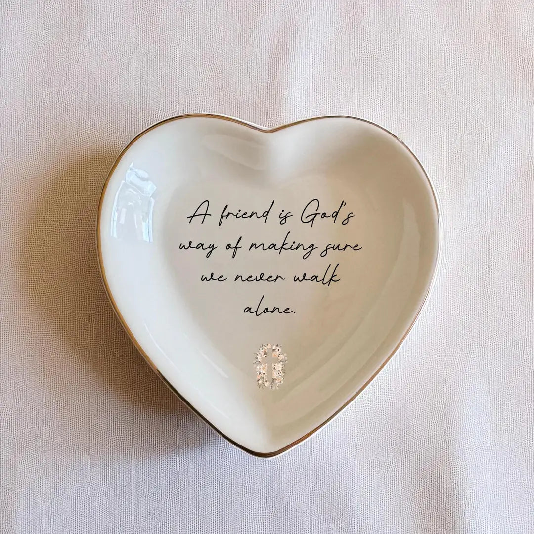 Heart-shaped ceramic ring dish with gold rim and the quote A Friend Is God's Way of Making Sure We Never Walk Alone with a floral cross