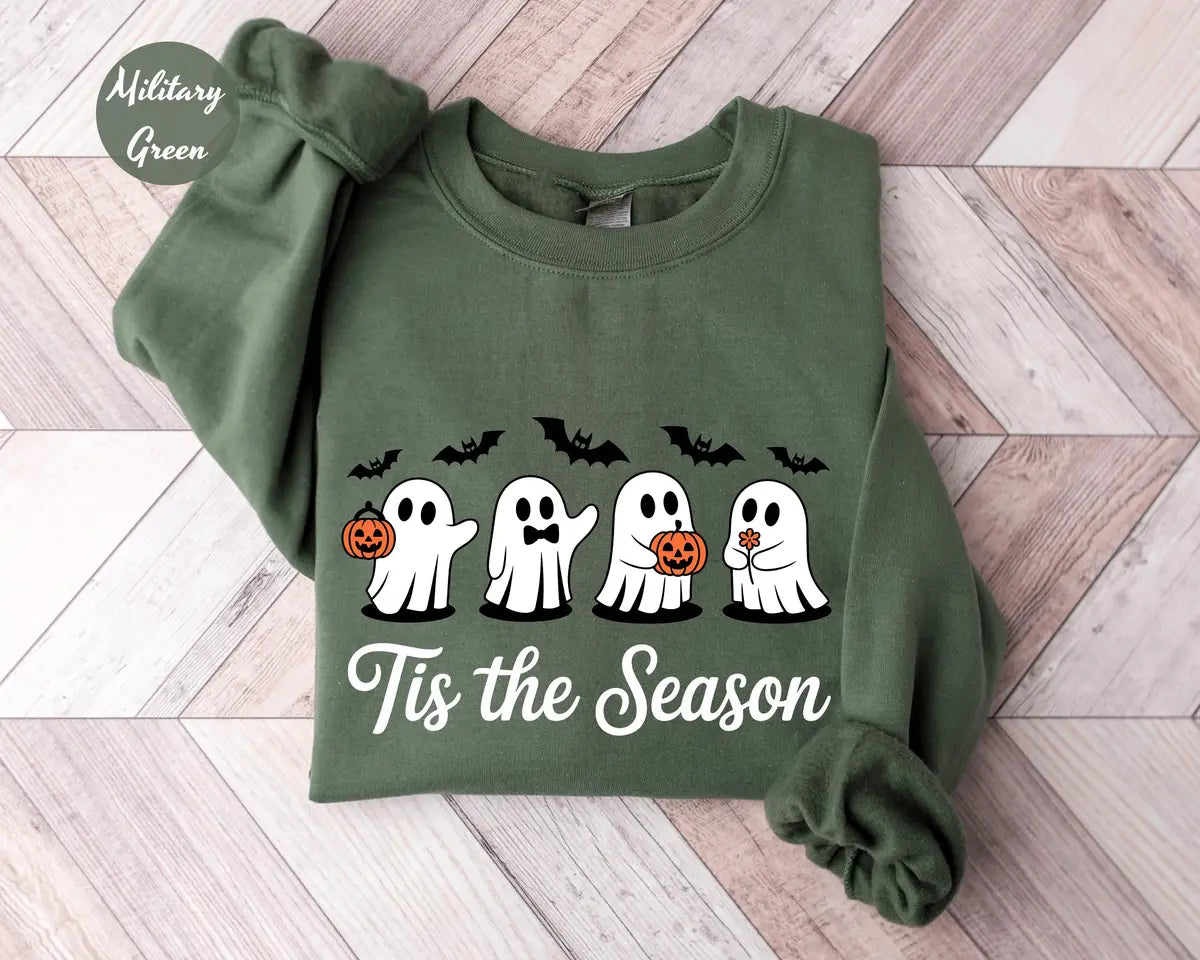 Military Green crewneck sweatshirt with printed four cute ghosts with pumpkins and bats above the words tis the season, flat lay view.