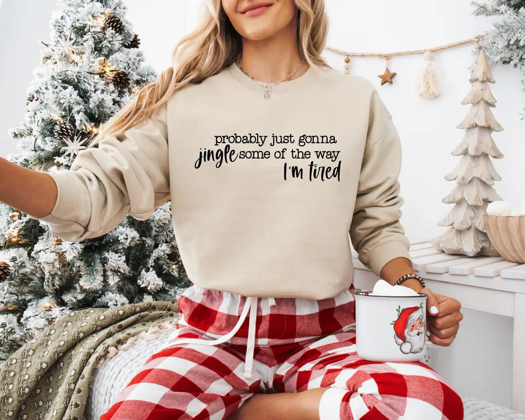 Sand crewneck sweatshirt with script lettering that reads probably just gonna jingle some of the way I'm tired, worn by a model.