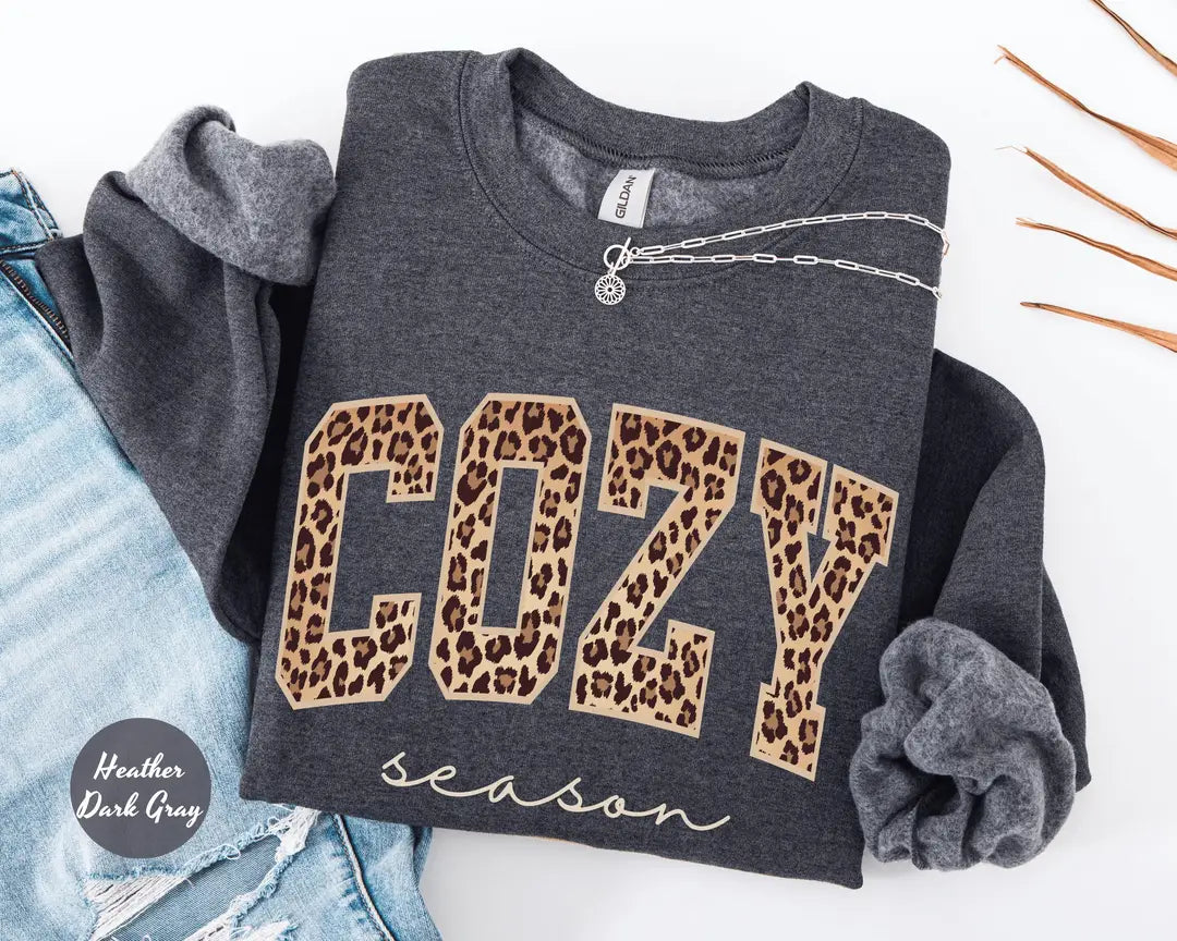 Heather Dark Gray crewneck sweatshirt with bold leopard print cozy lettering above the script words season, flat lay view.