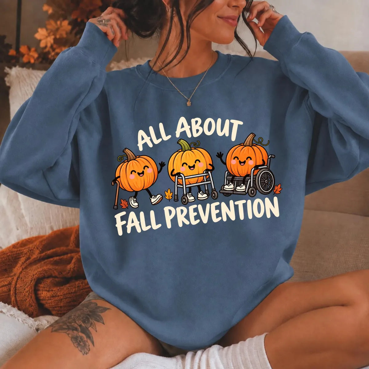 Indigo Blue crewneck sweatshirt with printed pumpkins with a walker and wheelchair above the words all about fall prevention, worn by a model.