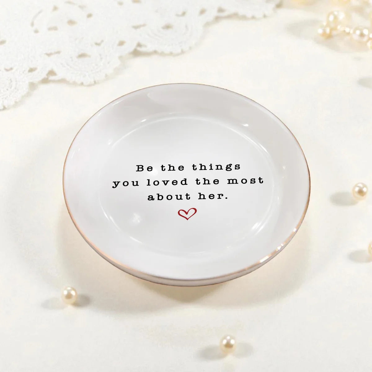 Round ceramic memorial ring dish with the quote Be the things you loved the most about her, styled with pearls and lace