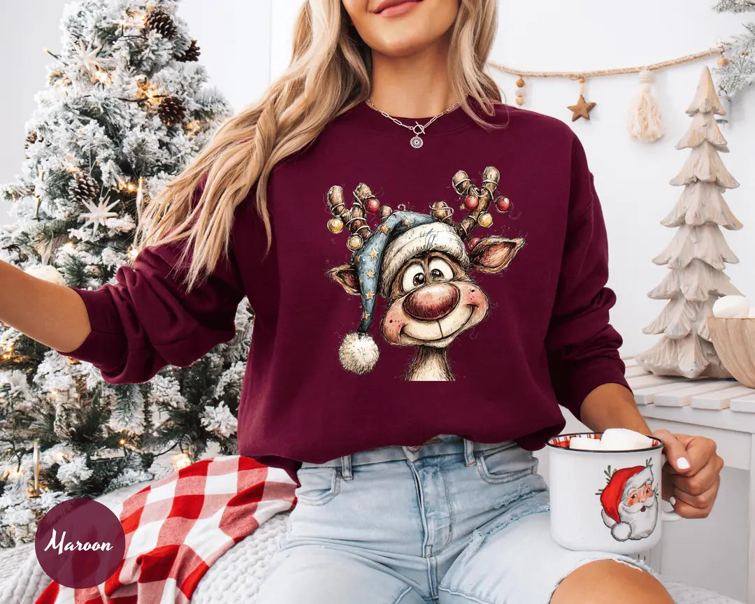 Maroon crewneck sweatshirt with a retro reindeer wearing a knit hat with ornament antlers, worn by a model.