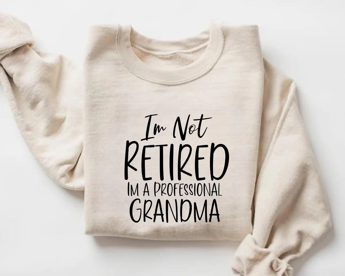 White Crewneck sweatshirt with I'm Not Retired I'm A Professional Grandma design, hero view.