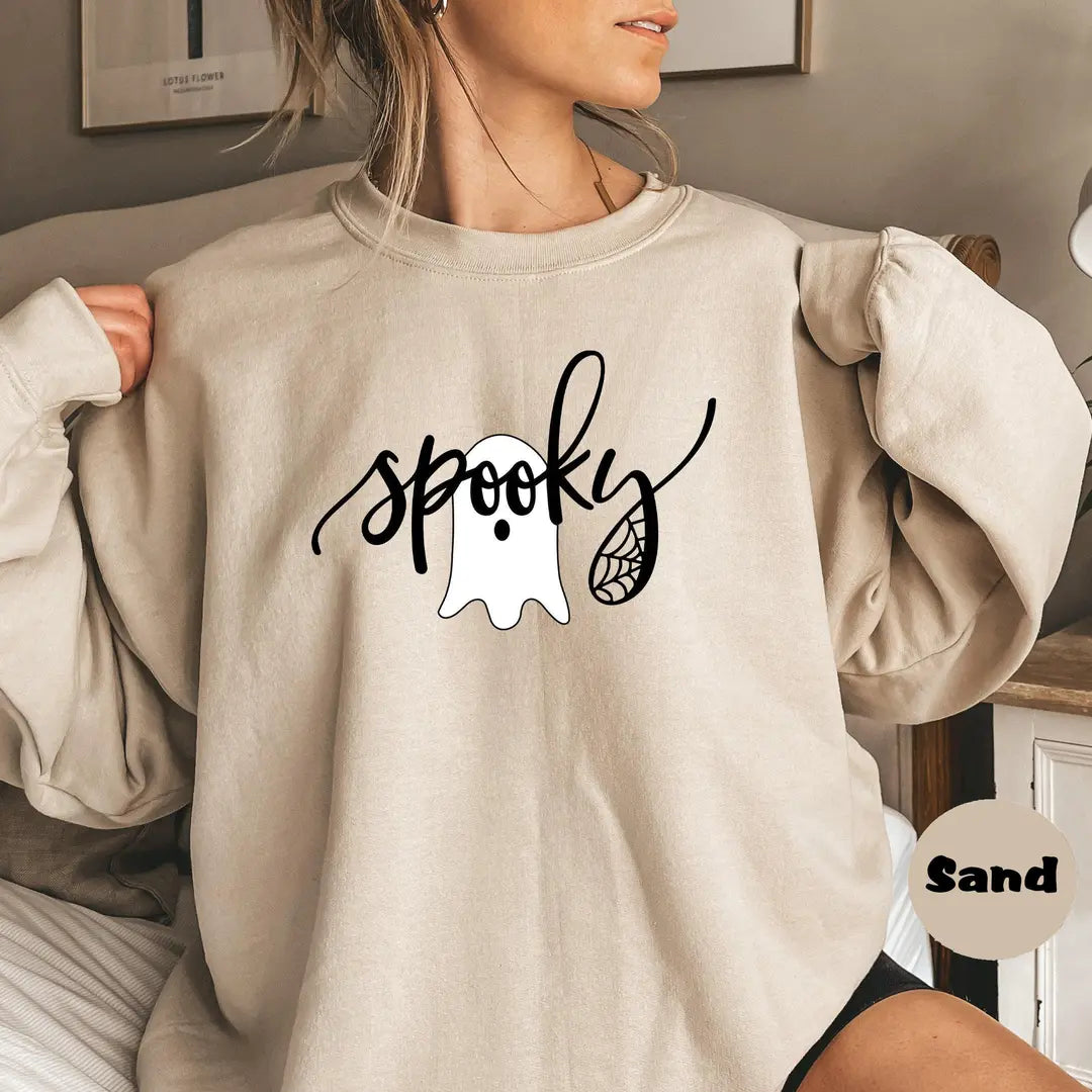Sand crewneck sweatshirt with the script word spooky with a ghost and spider web, worn by a model.