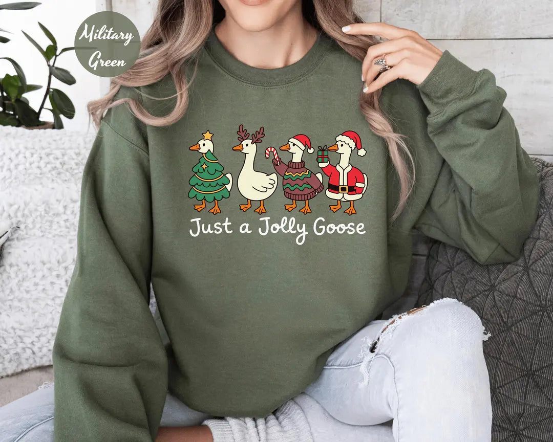 Military Green crewneck sweatshirt with geese dressed as a Christmas tree, reindeer and Santa above the words just a jolly goose, worn by a model.