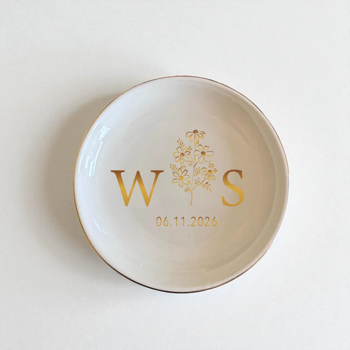 Round ceramic engagement ring dish with gold rim and gold initials with a custom date