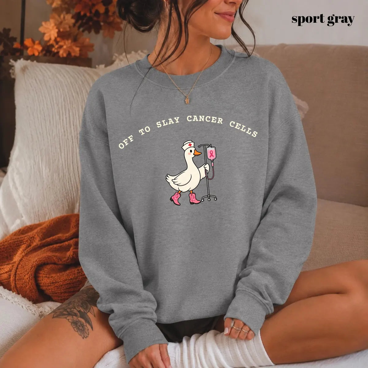 Sport Grey crewneck sweatshirt with printed a nurse goose in pink boots with an IV pole and the words off to slay cancer cells, worn by a model.