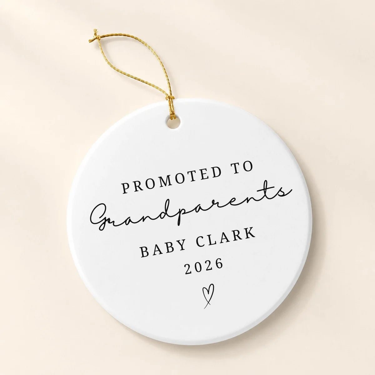 Round white ceramic Promoted to Grandparents ornament with a personalized baby name, year, and small heart on a cream background
