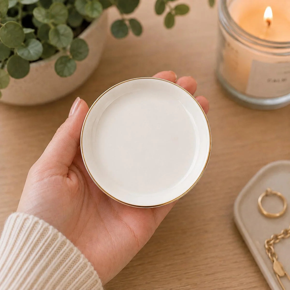 Hand holding a plain round ceramic ring dish with a gold rim and no printed design