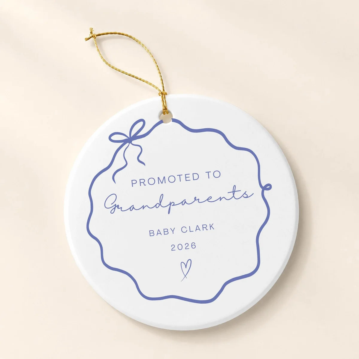 Blue wavy bow frame round ceramic Promoted to Grandparents ornament with a small heart, a personalized name and year, and a gold hanging string on a cream background