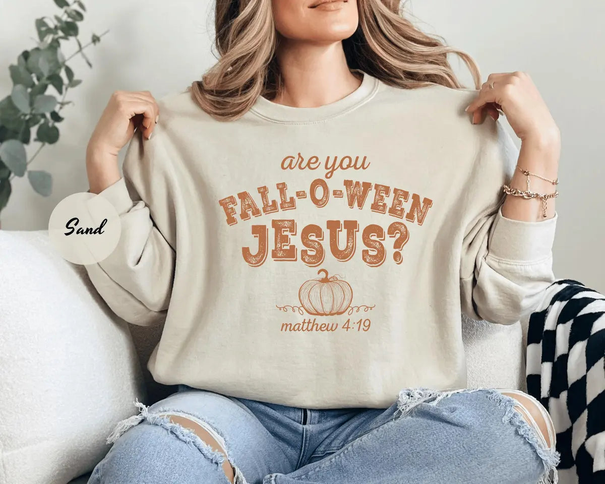 Sand crewneck sweatshirt with printed a pumpkin with the words are you fall-o-ween jesus and matthew 4:19 in a western style font, worn by a model.