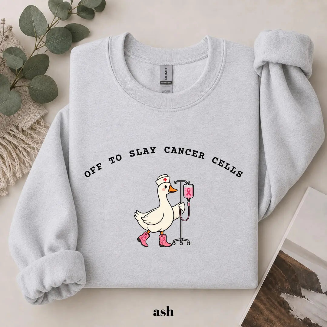 Ash crewneck sweatshirt with printed a nurse goose in pink boots with an IV pole and the words off to slay cancer cells, flat lay view.