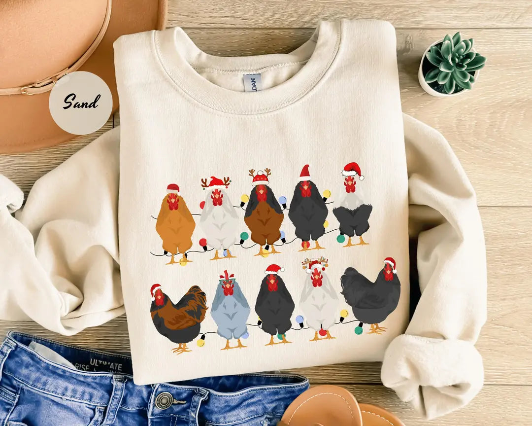 Sand crewneck sweatshirt with two rows of colorful chickens wearing Santa hats, flat lay view.